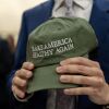 Close-up of a hand clutching a green baseball cap with this written on it "Let's make America healthy again." 