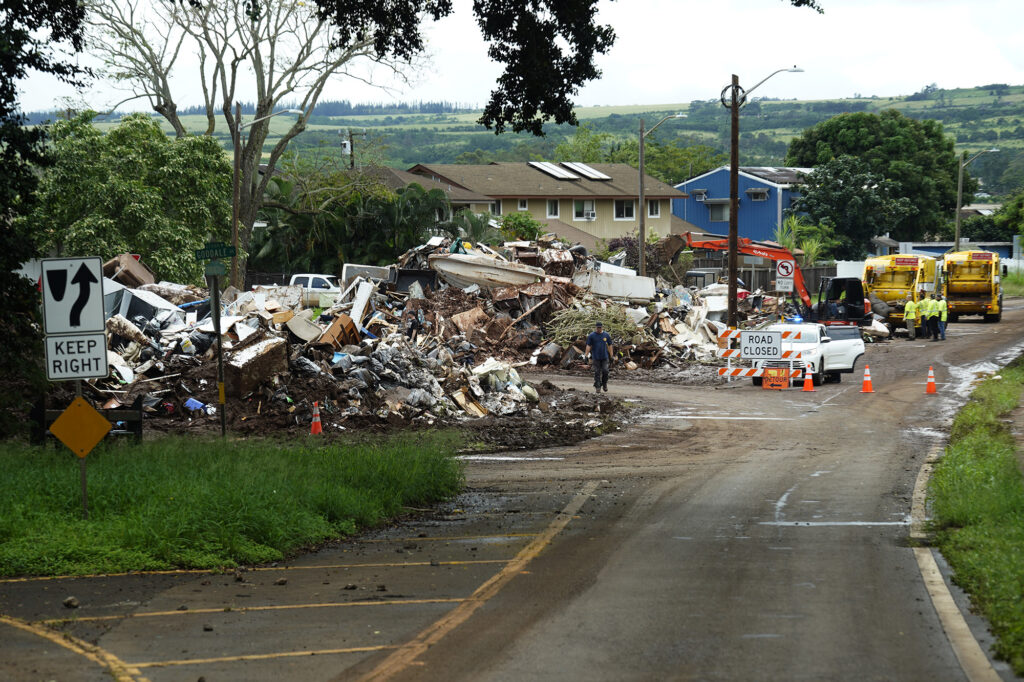 Trash is piled up in the middle of a roundabout in Waialua on Monday, March 23, 2026. The traffic circle serves as a makeshift trash transfer center for nearby homes damaged by storm Kona flooding. (Kevin Fujii/Civil Beat/2026)