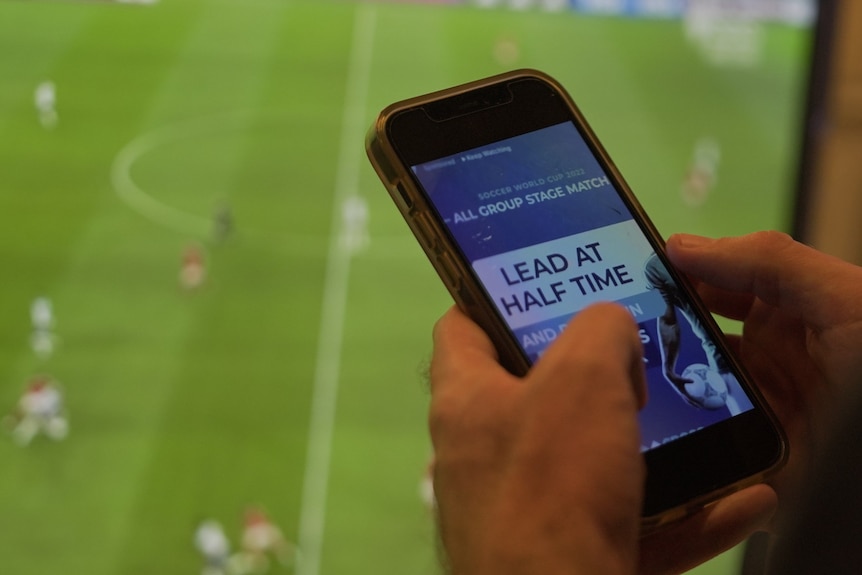 Hand holding mobile phone displaying gambling app.