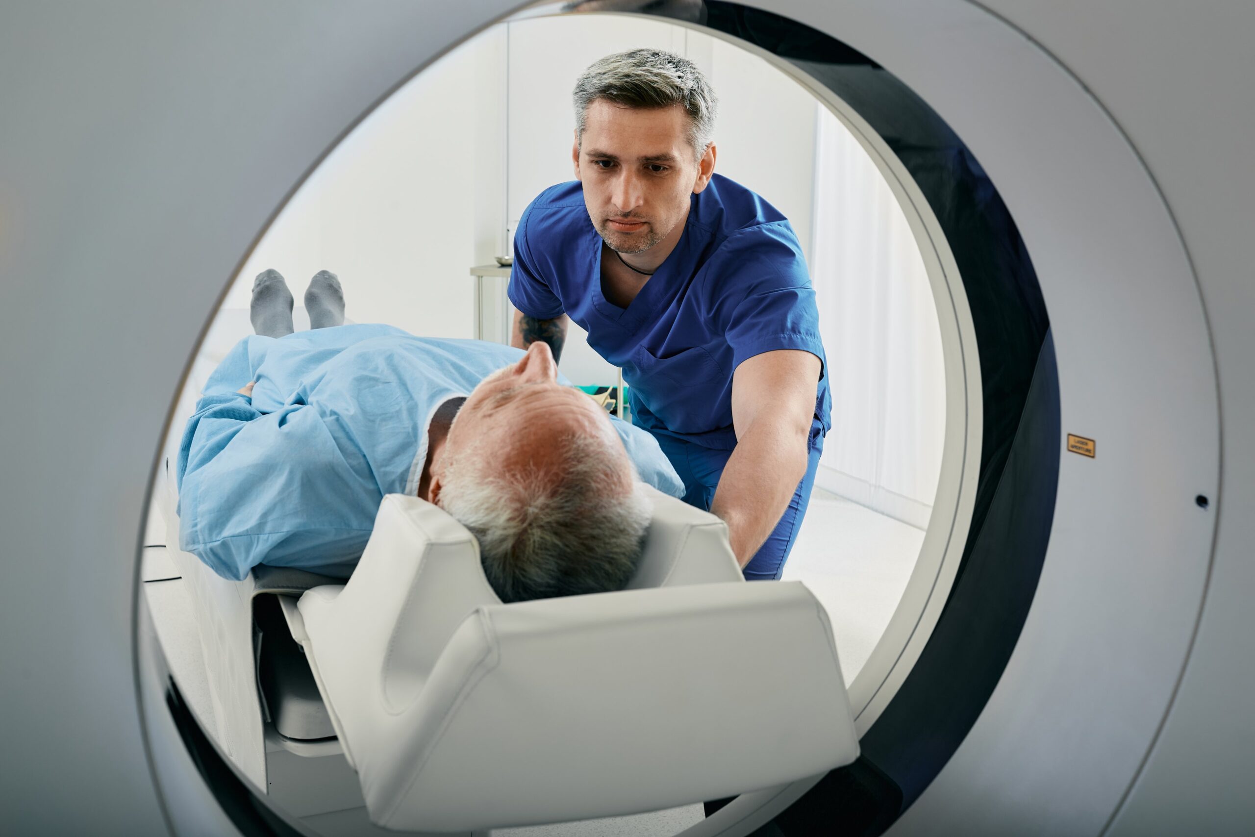 A medical professional assisting a person inside an MRI machine.