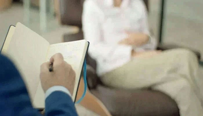 This representative image shows a professional writing in a diary during counseling. — pixels/file